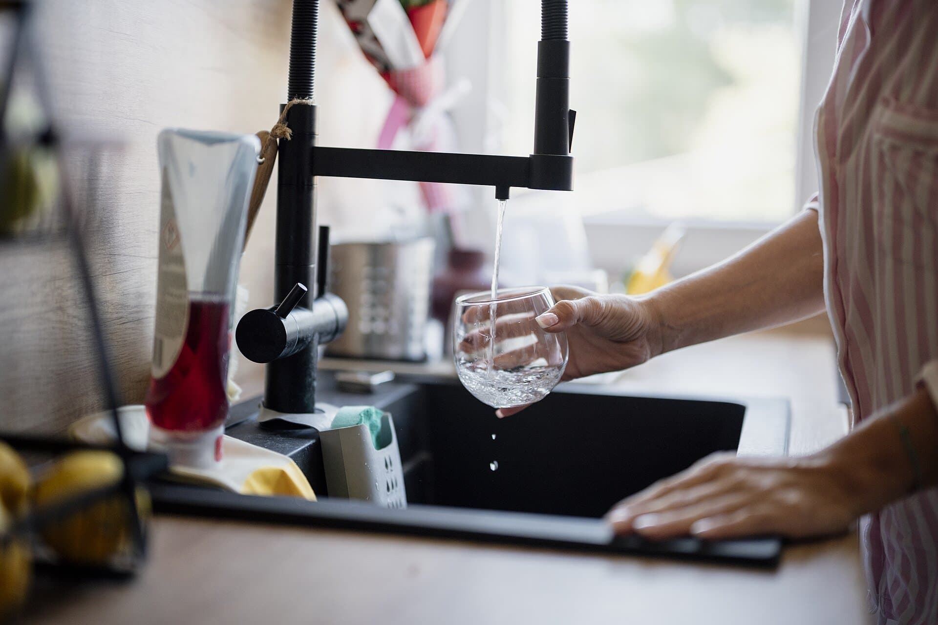 Filling a glass with water at a kitchen sink