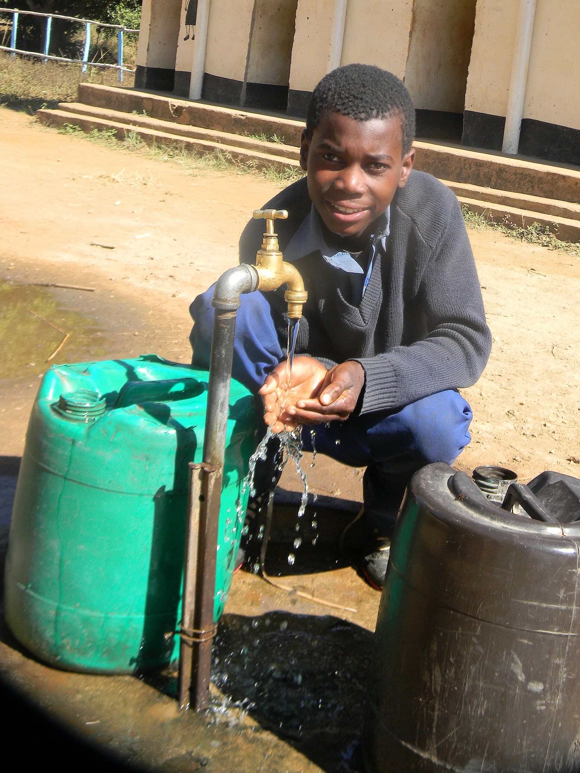A school-age child drinking a glass of water